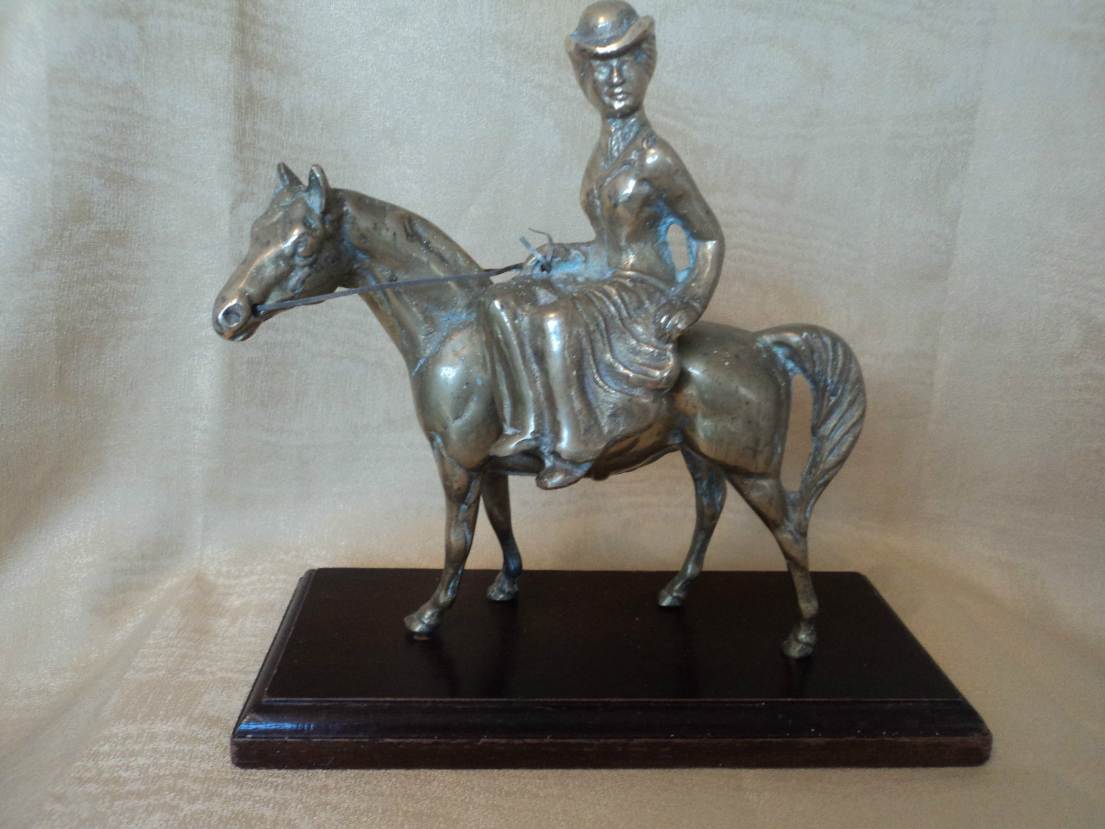 Pequeña figura decorativa de un jinete a caballo sobre base de madera oscura
